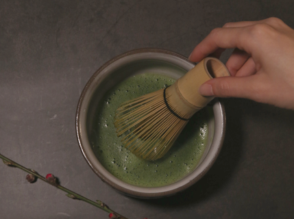 Japanese matcha being prepared with a bamboo whisk
